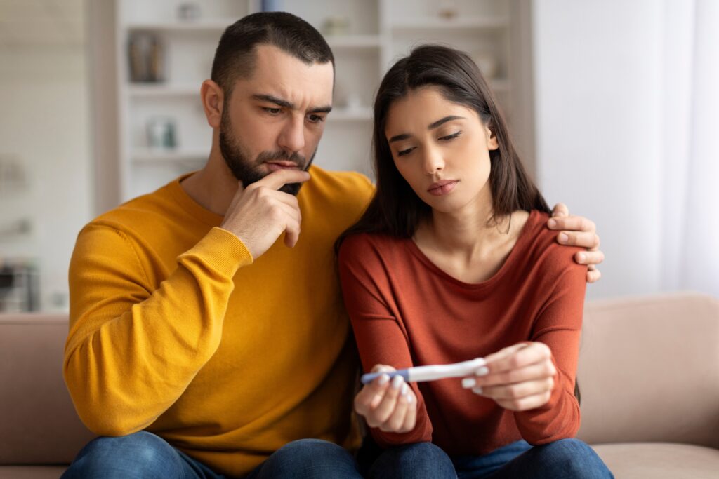 Photo d'un couple devant un test de grossesse avec un résultat négatif. 
