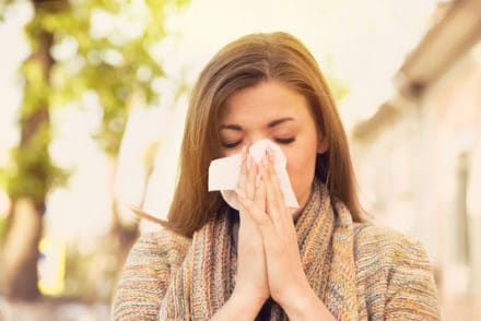femme souffrant d'allergies saisonnières entrain de se moucher