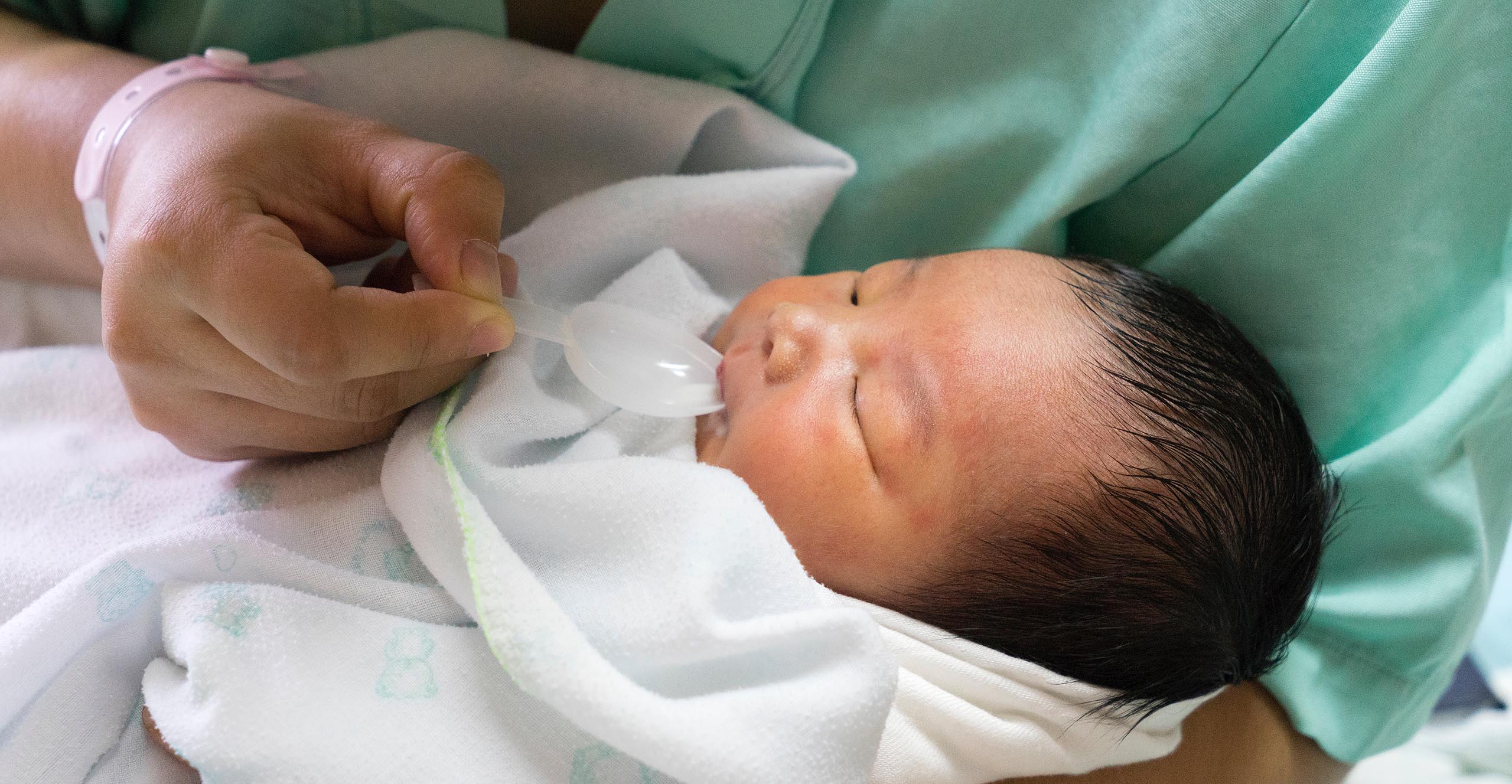 nouveau-né recevant des gouttes de vitamine D dans une cuillère