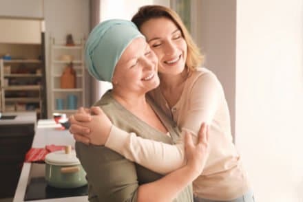femmes tenant dans ses bras une autre femme atteinte de cancer et ayant perdu ses cheveux