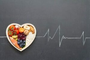 plat en forme de coeur rempli d'aliments sains posé sur un dessin d'électrocardiogramme