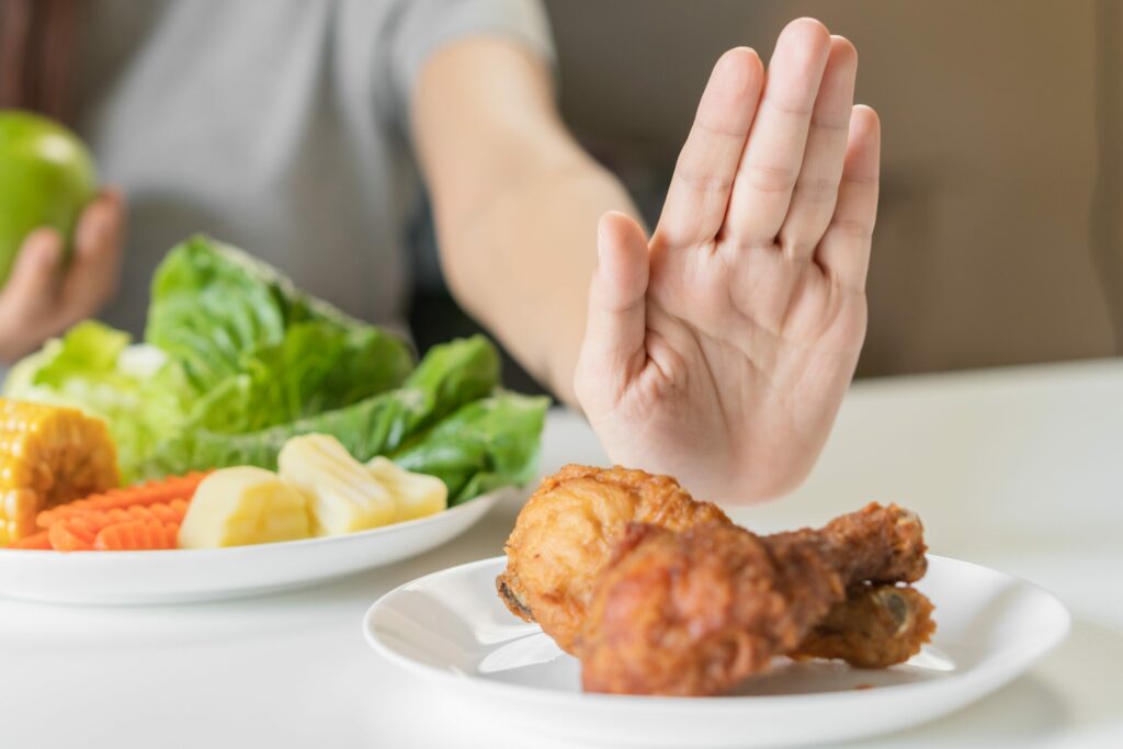 Une femme refuse de une assiette contenant du poulet frit d'un geste de la main.