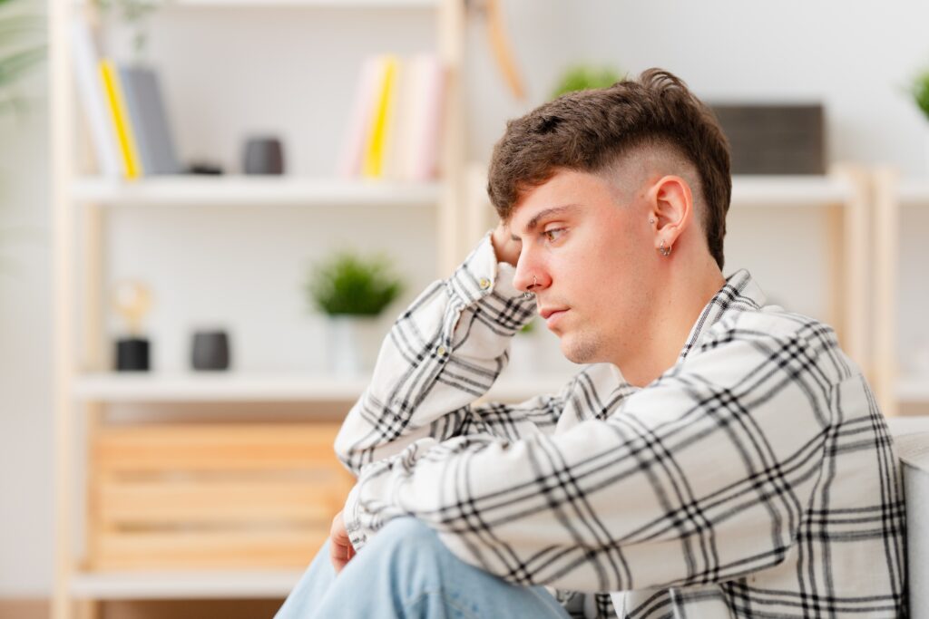 Un homme est assis sur un canapé et son visage triste évoque la dépression.