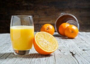 verre de jus d'orange à côté d'une orange coupée en deux
