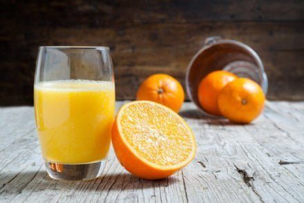 verre de jus d'orange à côté d'une orange coupée en deux