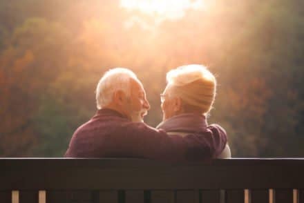 couple de personens âgées assises sur un banc dans le soleil couchant