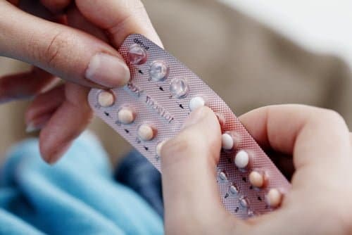 vue rapprochée de deux mains tenant une plaquette de pilules contraceptives