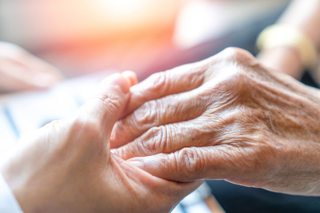 Photo d'une main de soignant tenant la main d'une personne âgée.