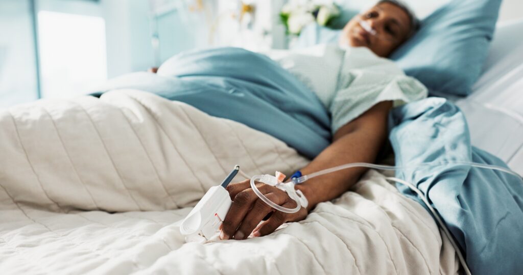 Une femme sous perfusion est allongée sur un lit d'hôpital.