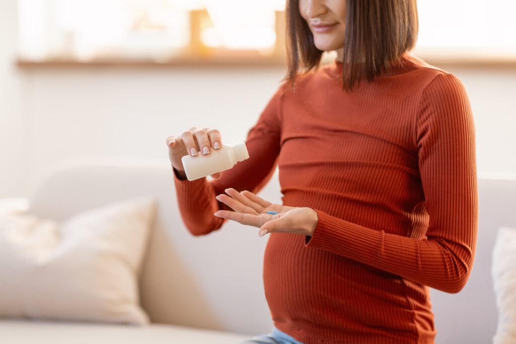 Une femme enceinte verse un comprimé dans sa main.