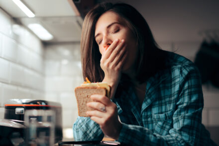 Une femme fatiguée mange un sandwich